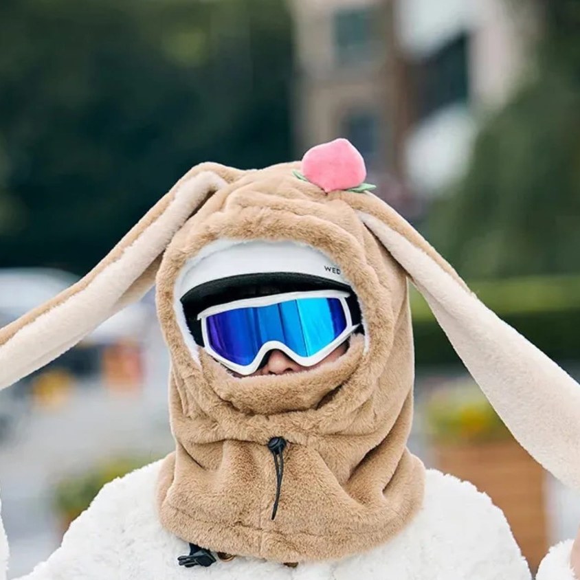 Beiger Plüsch-Hasen-Helmüberzug mit Pfirsich über Helm und Skibrille